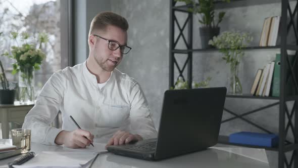 Young Male Entrepreneur Working at Computer Conducts Business Online Happy From Work Done