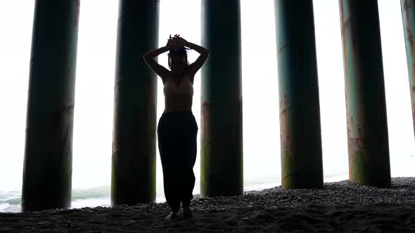 Female Silhouette Against the Background of Dark Pillars