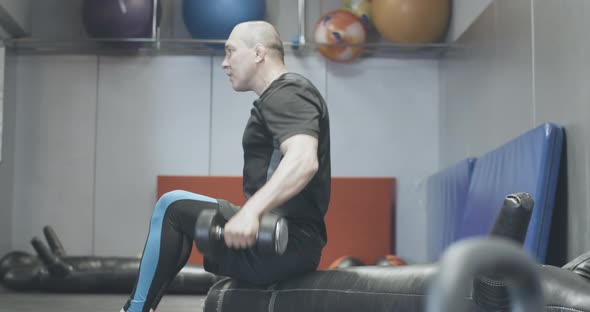 Side View of Confident Man Lifting Hand Weights in Gym. Serious Handsome Caucasian Sportsman alt