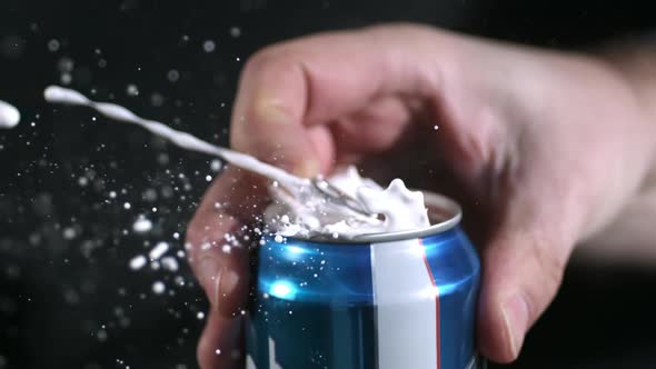 Rotating slow motion of aluminum can spewing liquid as tab is pulled. alt