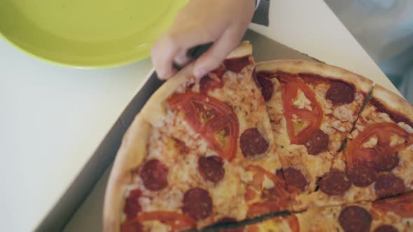 Child Puts Large Pizza Slice on Plate Closeup Upper View