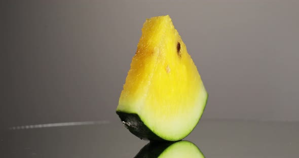 A Slice of Yellow Watermelon Rotates 360 Degrees on a Gray Background
