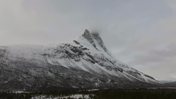 Scenic mountain in arctic dominates snow white winter landscape; aerial