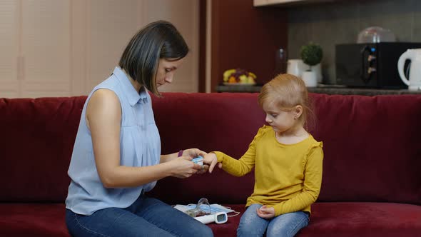 Mother Measuring, Monitoring Oxygen Saturation with Digital Pulse Oximeter of Her Daughter at Home