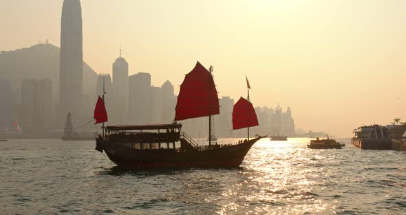 Sunset skyline of Hong Kong with traditional cruise sailboat at Victoria harbor