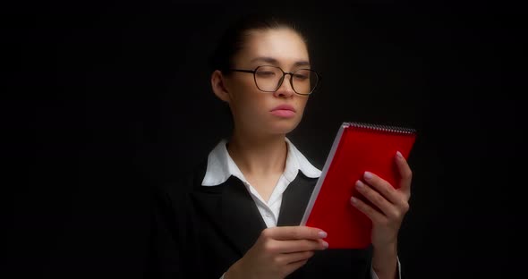 Business Woman is Outraged By What She Has Read in a Red Notebook