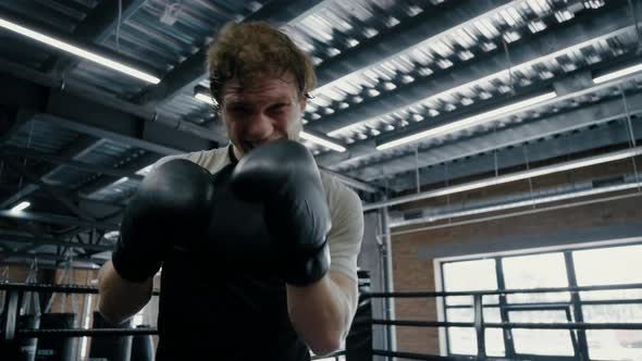 Anxious Fighter Exercising in Box at Gym. Sportsman Making Progress on Ring