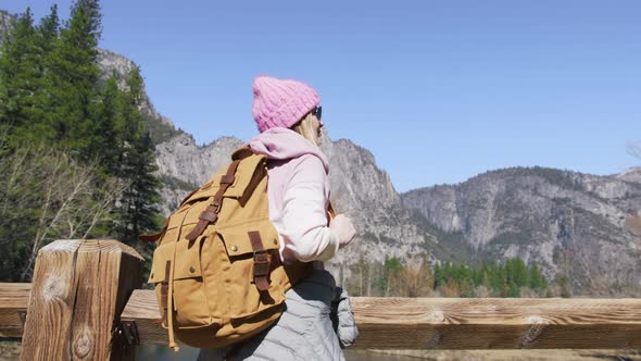 Woman Traveler with Tourist Backpack on Wooden Bridge in Green Yosemite Forest