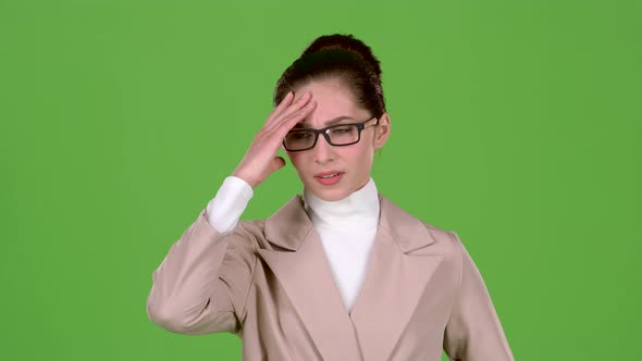 Girl in a Business Suit Is Standing in the Studio, She Has Terrible Headaches. Green Screen. Slow