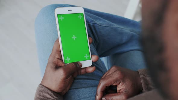 African American Man with Smartphone at Home. Green Screen or Mock Up Display on Mobile Phone