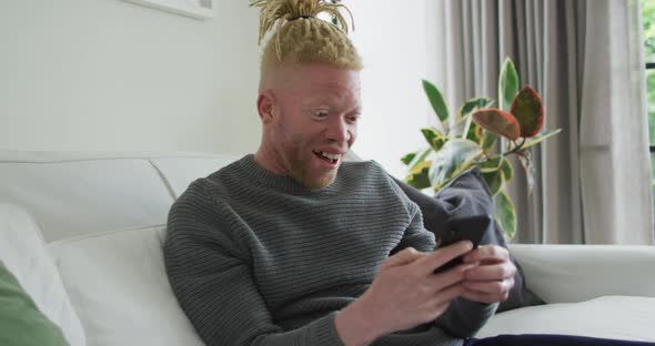 Albino african american man with dreadlocks using smartphone