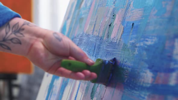 A Chubby Woman Paint Artist Drawing an Abstract Blue Painting with a Brush and Oil Paints