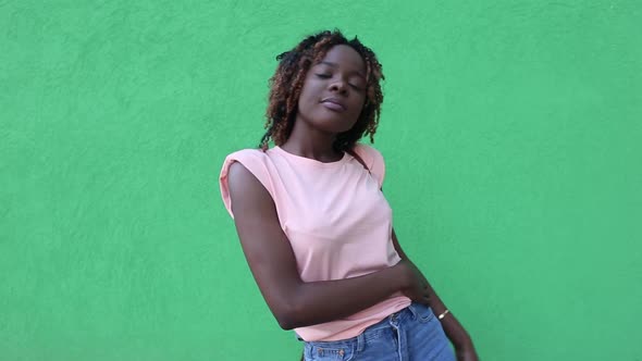 happy African-American woman dances and blows a kiss, on a green background