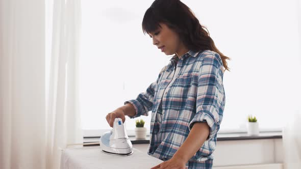Asian Woman Ironing Bed Linen at Home