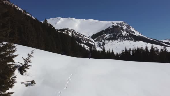 Man Walking Toward Mountain in Winter