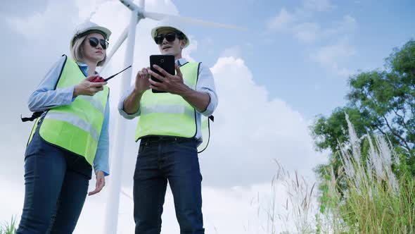 Two engineers are standing together discussing wind power projects and work