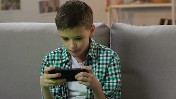 Boy Playing Video Game on Smartphone at Home, Gadget Addiction in Young Age