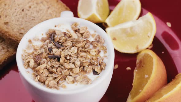 Cup of White Greek Yogurt with Crunchy Granola in a Rotating Red Plate