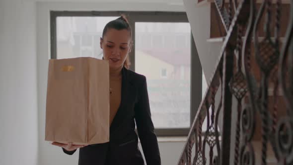 Businesswoman Climbing Stairs in Startup Company Office Hoding Takeaway Food Meal Bag