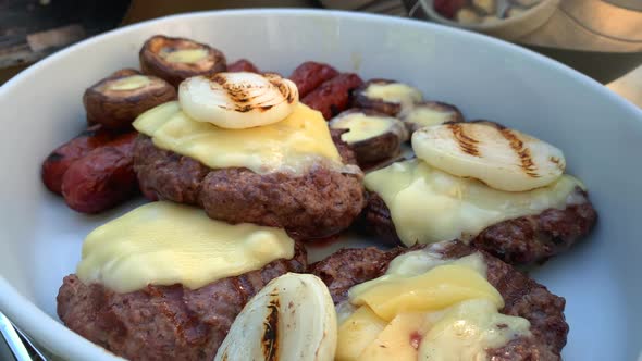 Grilled Burgers Sausage and Mushrooms on a White Plate