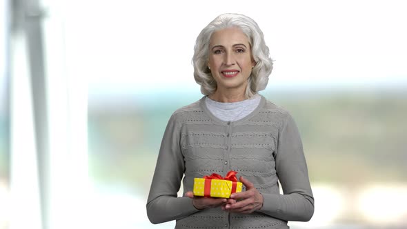 Portrait of Senior Woman Presenting Gift Box.