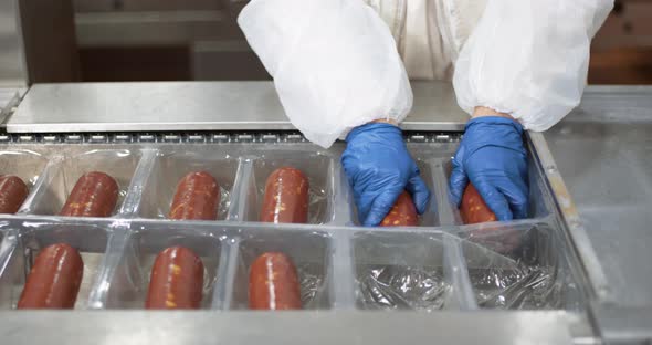 Meat Production, Woman Worker in Protective Uniforms Pack and Stack Raw Smoked Sausages, the Process