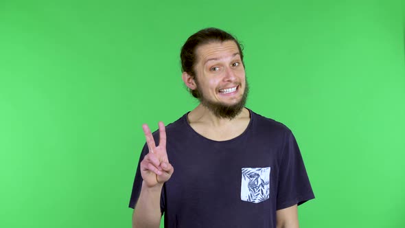 Portrait of a Young Man Shows a Victory Gesture with Two Fingers