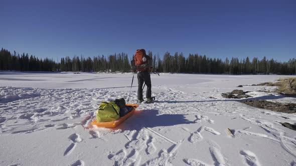 Man pulling sled in the snow in the forest. Cross country winter expedition.