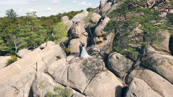 Wedding Couple in Mountain Rock From Drone. Aerial View Happy Newlyweds in Love Hugging Standing