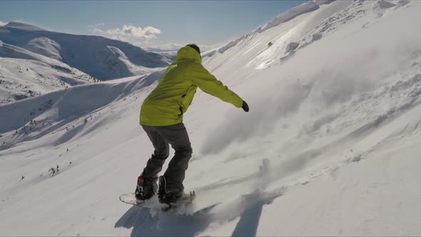 Side Shot of a Snowboarder Pulling Powder Spray in the Air While Riding a Mountain with a View