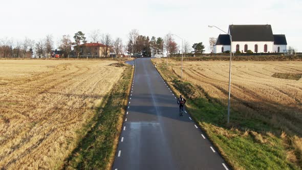 Man Skiing Up Swedish Countryside Rural Road Near Ostersund, Sweden During Sunset. 4K Drone.