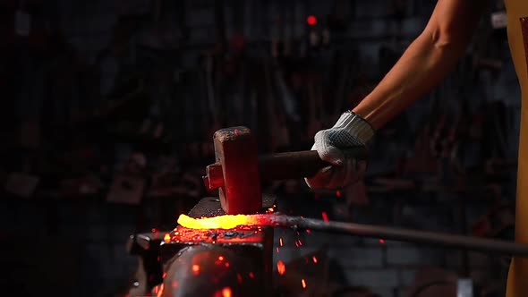 Slow Motion Close Up Hand with the Hammer of Blacksmith Man Forges a Metal Product in Dark Indoors