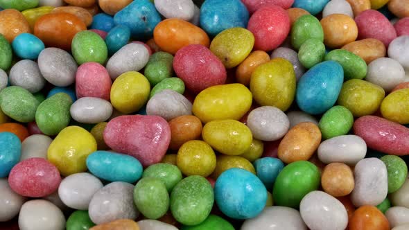 Pile of Many Round Chewy Candies Dragee in Multicolored Glaze Rotate Slowly on Turntable