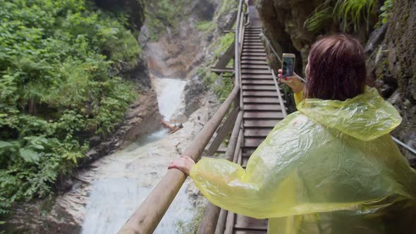 a Hiker in a Yellow Raincoat Taking Photo While Walking in a Mountain Canyon