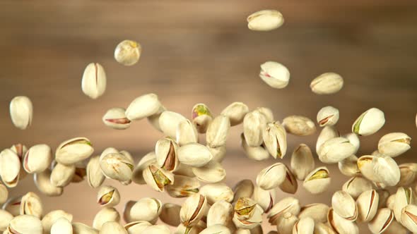 Super Slow Motion Shot of Flying Pistachios After Being Exploded on Wooden Background at 1000Fps