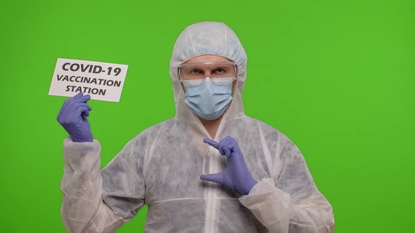 Medical Doctor in PPE Suit with Medicine Ampoule and Text on Paper  Covid19 Vaccination Station