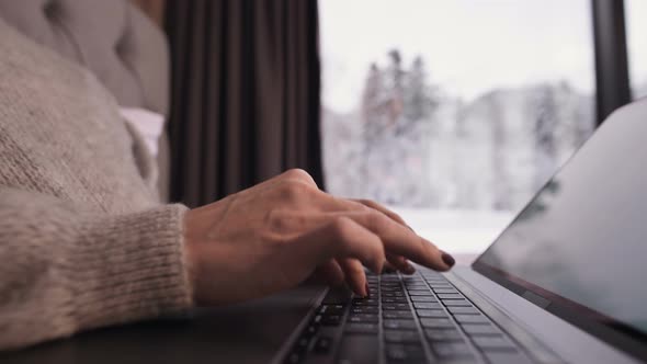 Close-up of the Girl Hands Print Something on the Laptop Sits on a Bed with a Laptop in Her Hands