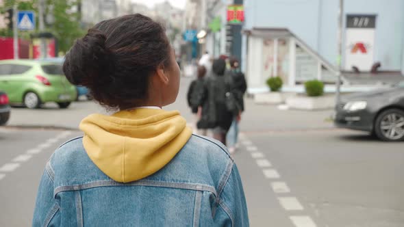 Back View of Stylish African American Woman in a Jean Jacket Walking City in the Downtown