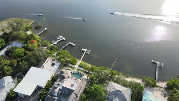 Flying over beach homes that line the Bay Area. The camera moves over open ocean water as boats pass