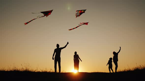 Active Family with Children Launches Kites in a Picturesque Place at Sunset