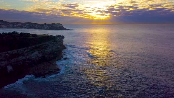 Flying towards the sun from Tamarama beach passing MacKenzies Point near Bondi beach NSW Australia.