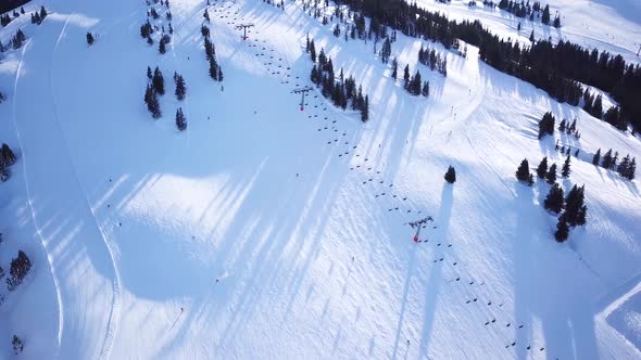 Panoramic top view from drone on cable way in ski resort. Ski lift elevator transporting skiers and