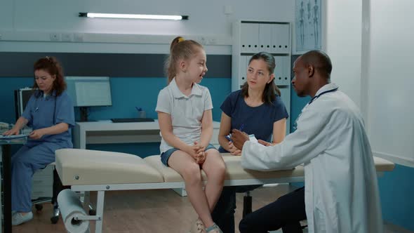 Doctor Taking Notes on Clipboard Documents to Examine Child