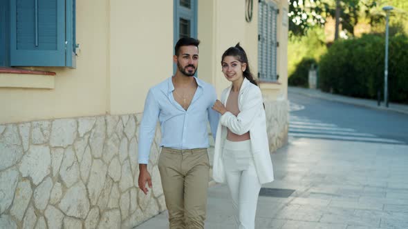 Happy Ethnic Couple Talking While Strolling on Urban Walkway