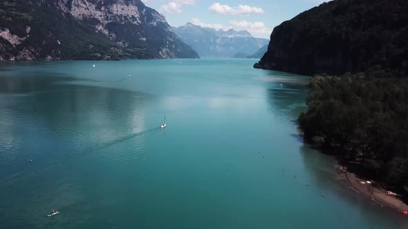 Aerial, drone rising shot of sailboats in a beautiful fjord lake in Switzerland while summer.