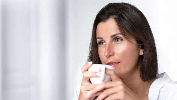 Closeup Portrait Satisfacted Smiling Woman Enjoying Tea or Coffee Indoor Holding Porcelain Cup