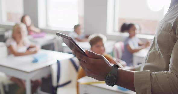 Video of hands of african american male teacher with tablet during lesson