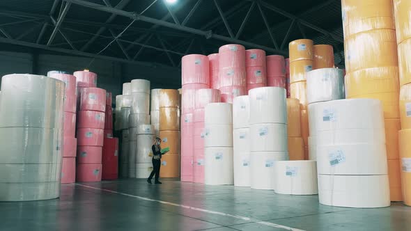 Female Specialist Observing a Large Warehouse Full of Paper Rolls