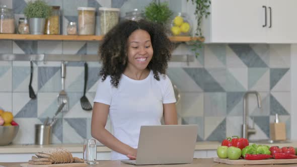 Young African Woman Doing Video Call on Laptop in Kitchen