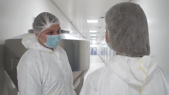 Two Laboratory Worker Discussing Work Standing in Interior in Modern Pharmaceutical Planta